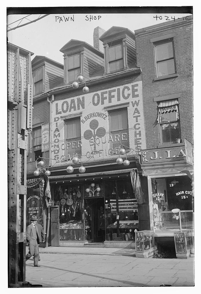 Black-and-white photograph of a 1910s American pawn shop storefront, the Cooper Square Loan Office, with the three pawnbroker balls hanging out front and signs reading LOAN OFFICE, DIAMONDS, and WATCHES.